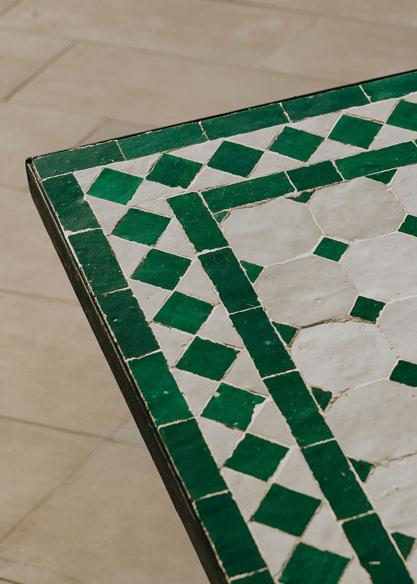 Mesa de azulejos exterior cuadrada con estructura de hierro forjado acabado en negro.