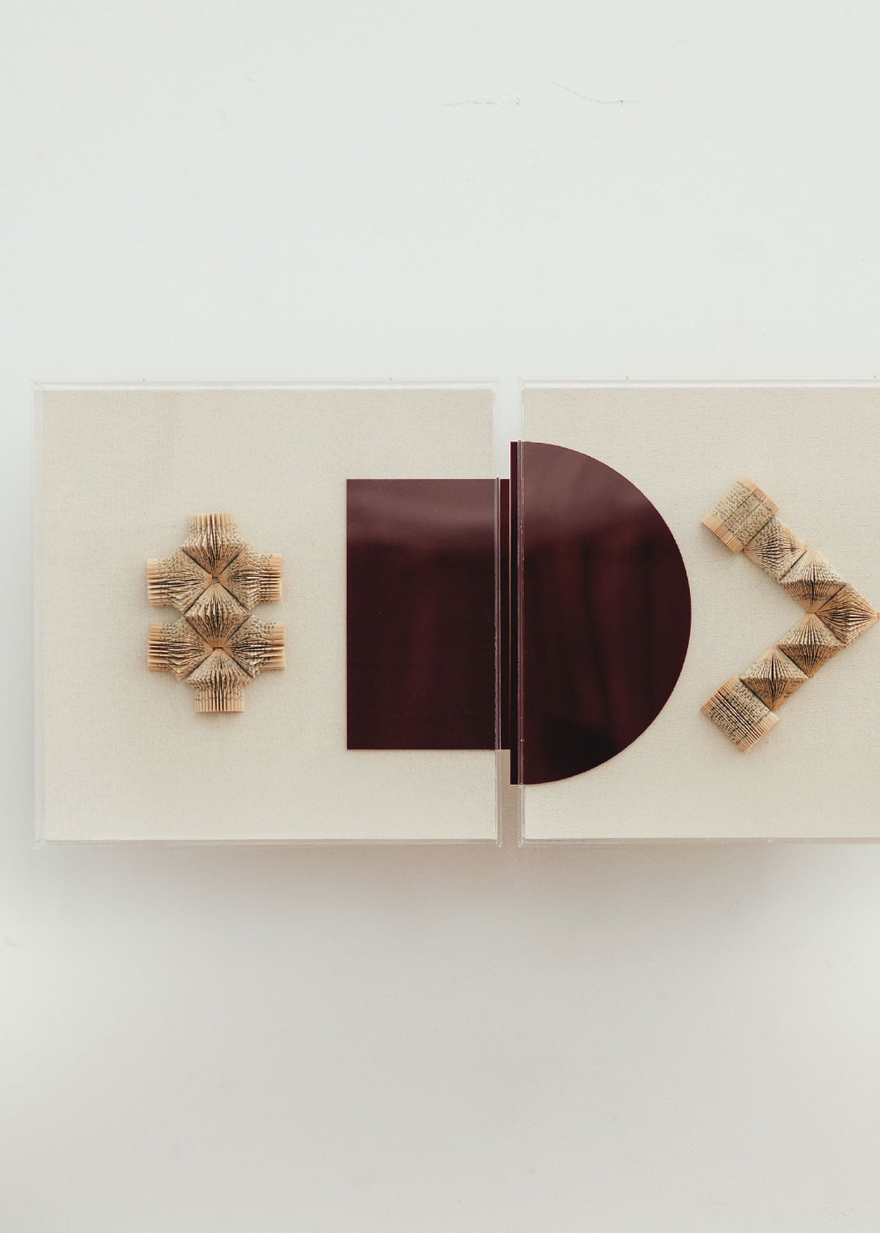 Escultura de pared forrada en lino rústico con caja de metacrilato transparente. Está formada por una serie de libros plegados y formas geométricas en metacrilato