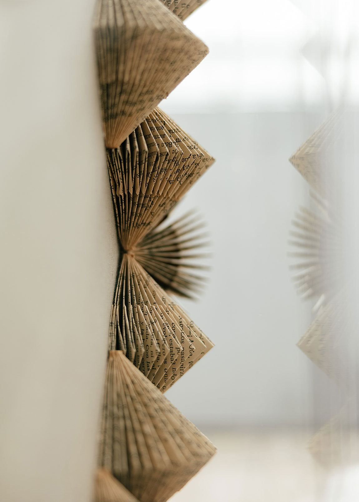 Escultura de pared forrada en lino rústico con caja de metacrilato transparente. Está formada por una serie de libros plegados y formas geométricas en metacrilato.
