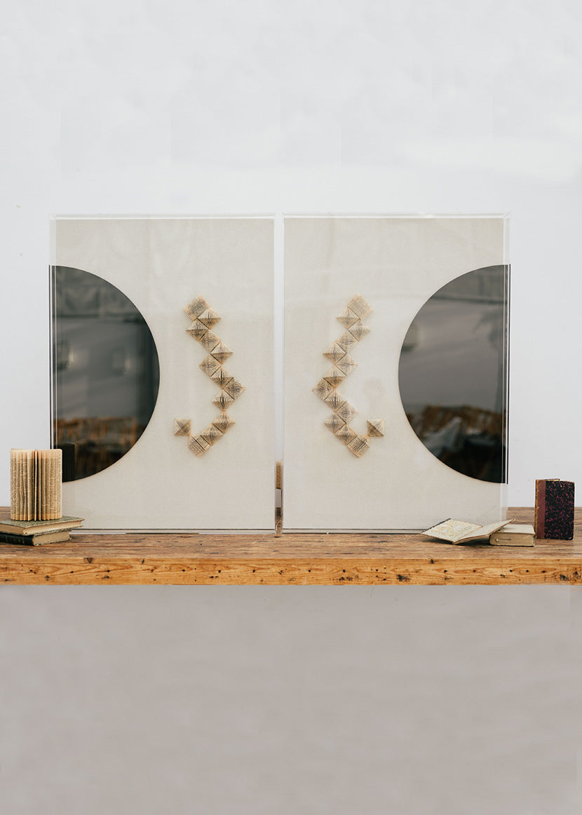 Escultura de pared en dos piezas forradas en lino rústico con cajas de metacrilato transparente. Está formada por una serie de libros plegados y formas geométricas en metacrilato.