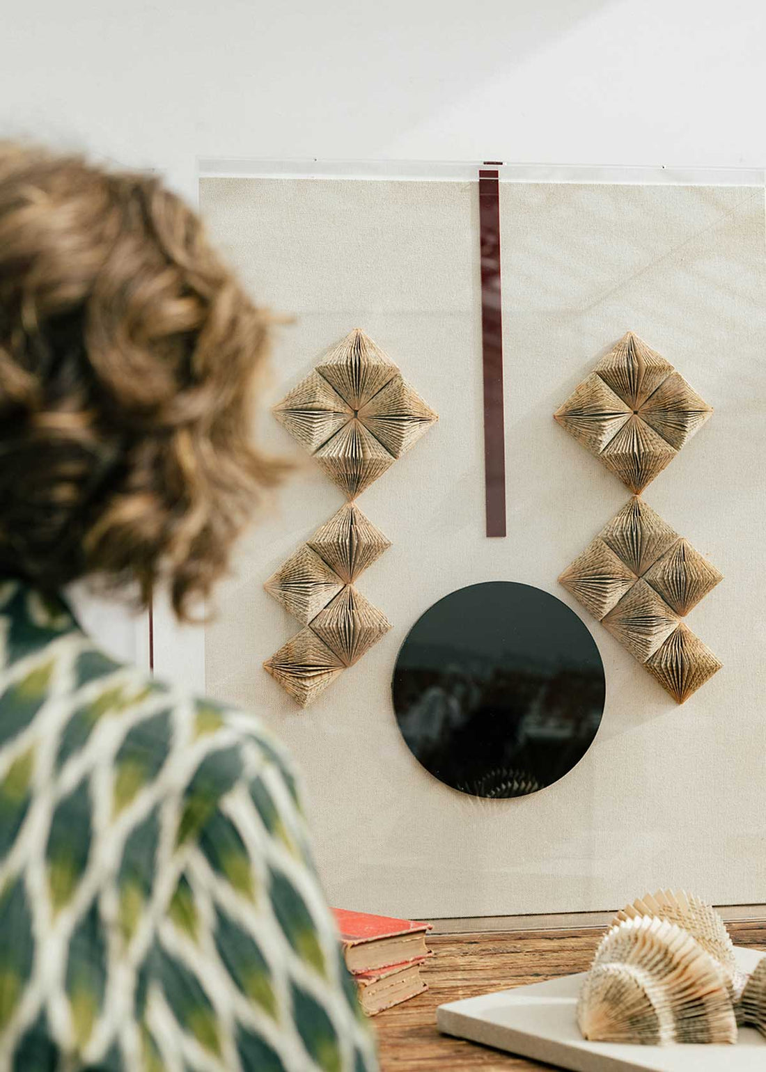 Escultura de pared forrada en lino rústico con caja de metacrilato transparente. Está formada por una serie de libros plegados y formas geométricas en metacrilato
