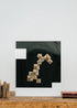 Escultura de pared forrada en metacrilato negro y blanco con caja de metacrilato transparente y serie de libros plegados.