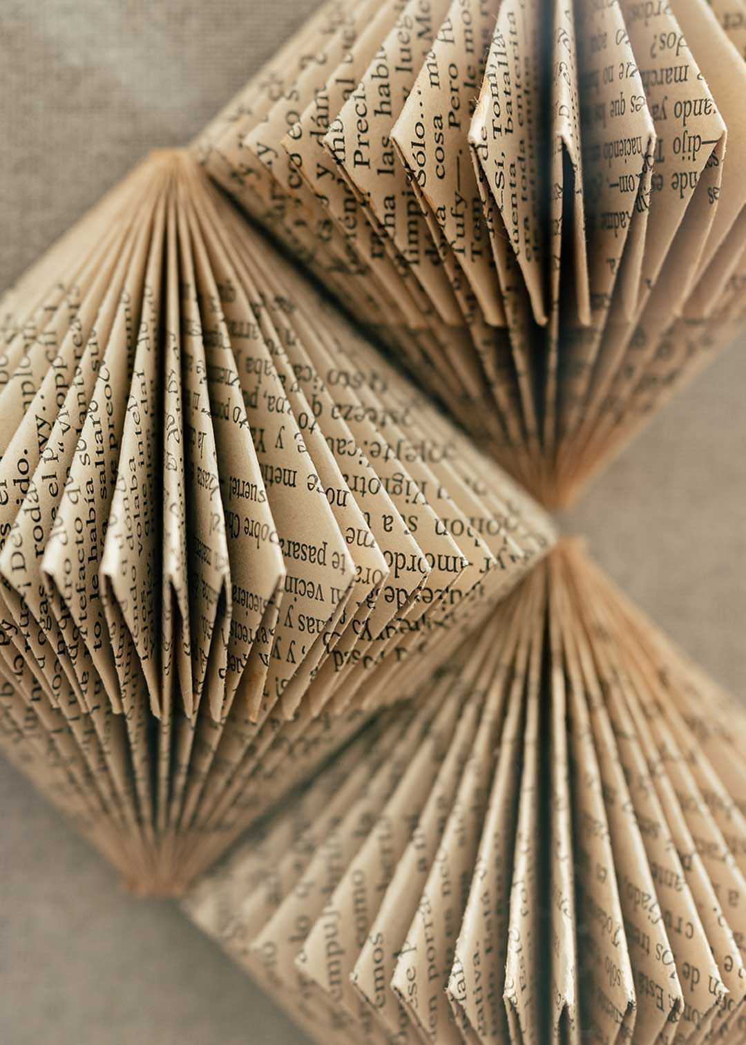 Escultura de pared forrada en lino rústico con caja de metacrilato transparente y serie de libros plegados.
