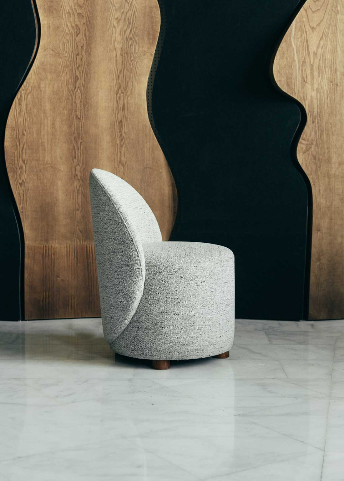 Butaca con estructura de madera tapizada con tela jaspeada en tonos crudos y patas de madera.