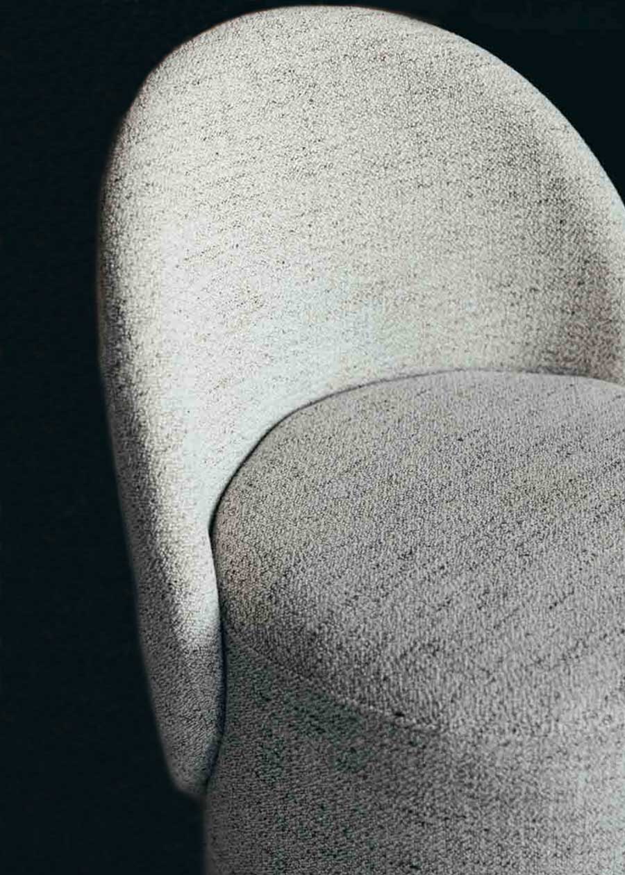 Butaca con estructura de madera tapizada con tela jaspeada en tonos crudos y patas de madera.