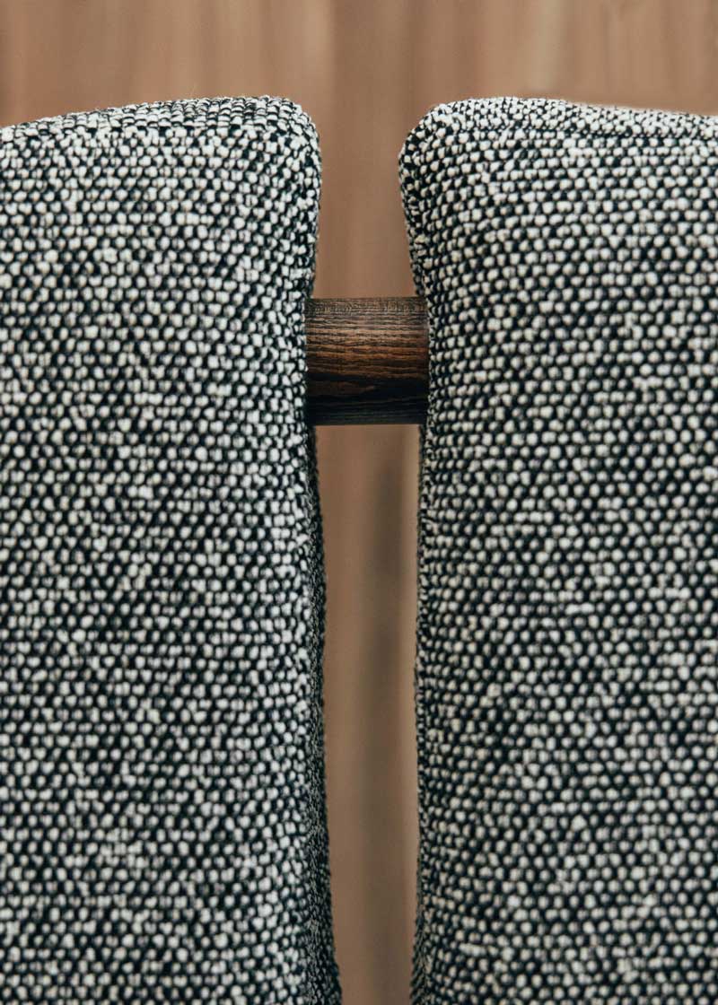 Silla de madera de haya con asiento tapizado en tela jaspeada en color blanco y negro.