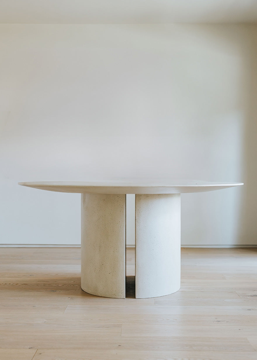 Mesa de comedor circular con estructura de madera revestida con microcemento.