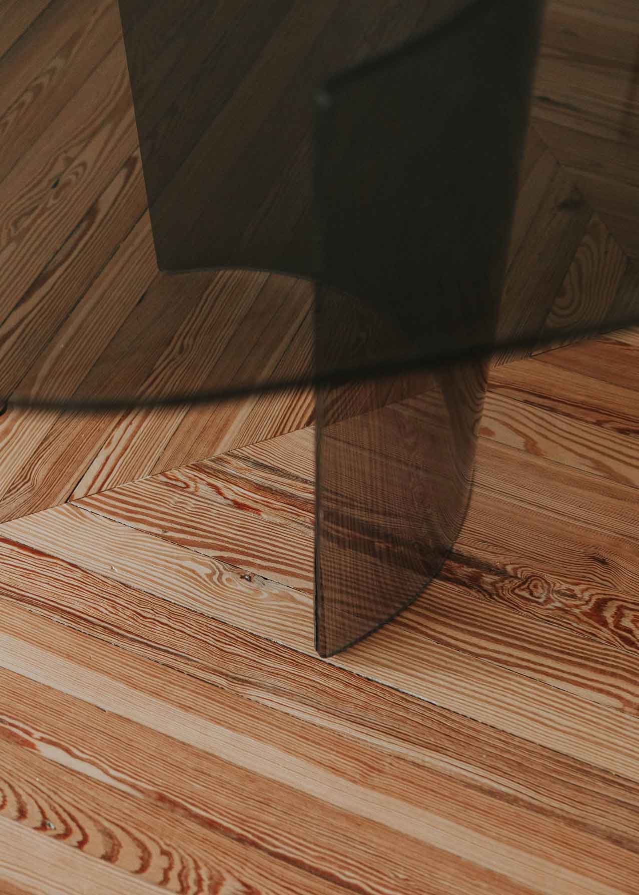 Mesa de comedor con sobre de vidrio ahumado y patas de metacrilato.