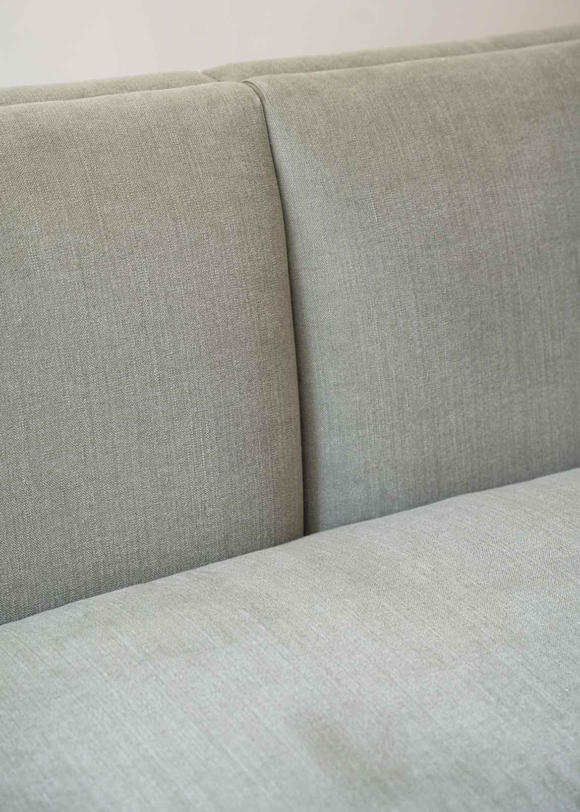 Sofá tapizado en tela gris de lino y algodón con estructura de madera de haya.