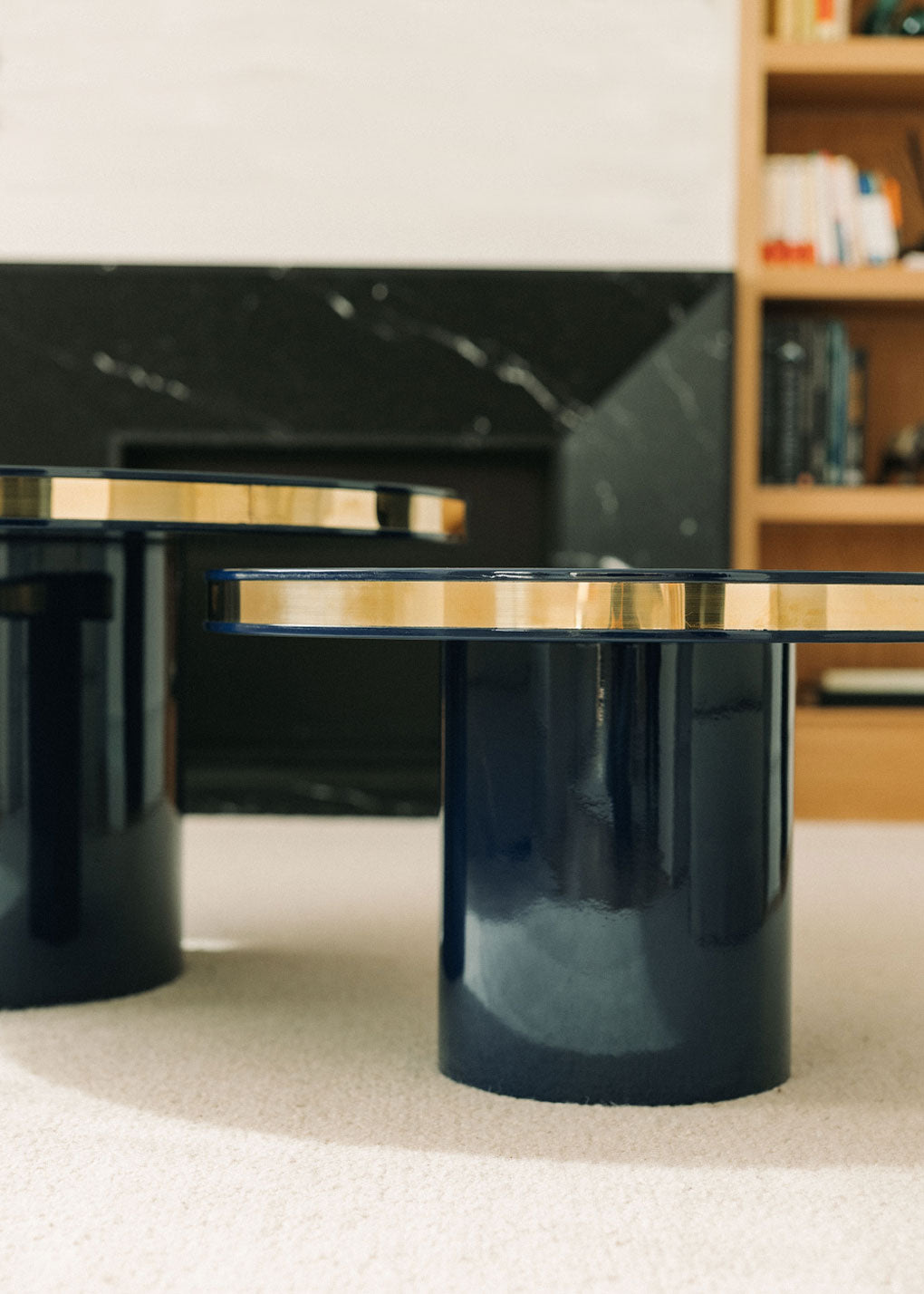 Conjunto de dos mesas circulares realizadas en madera lacadas en color negro con acabado brillo y detalle de latón.