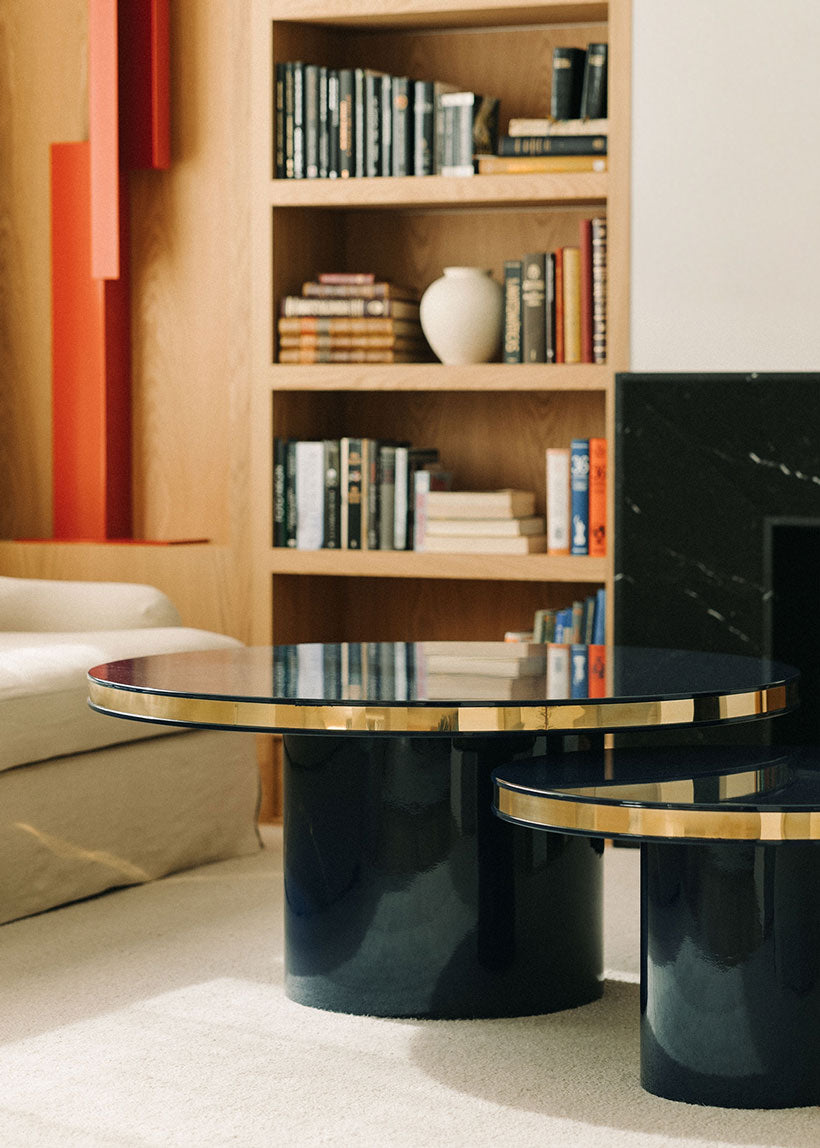 Conjunto de dos mesas circulares realizadas en madera lacadas en color negro con acabado brillo y detalle de latón.