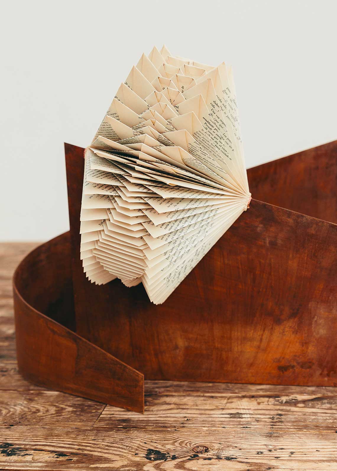 Escultura de hierro oxidado con libro plegado.