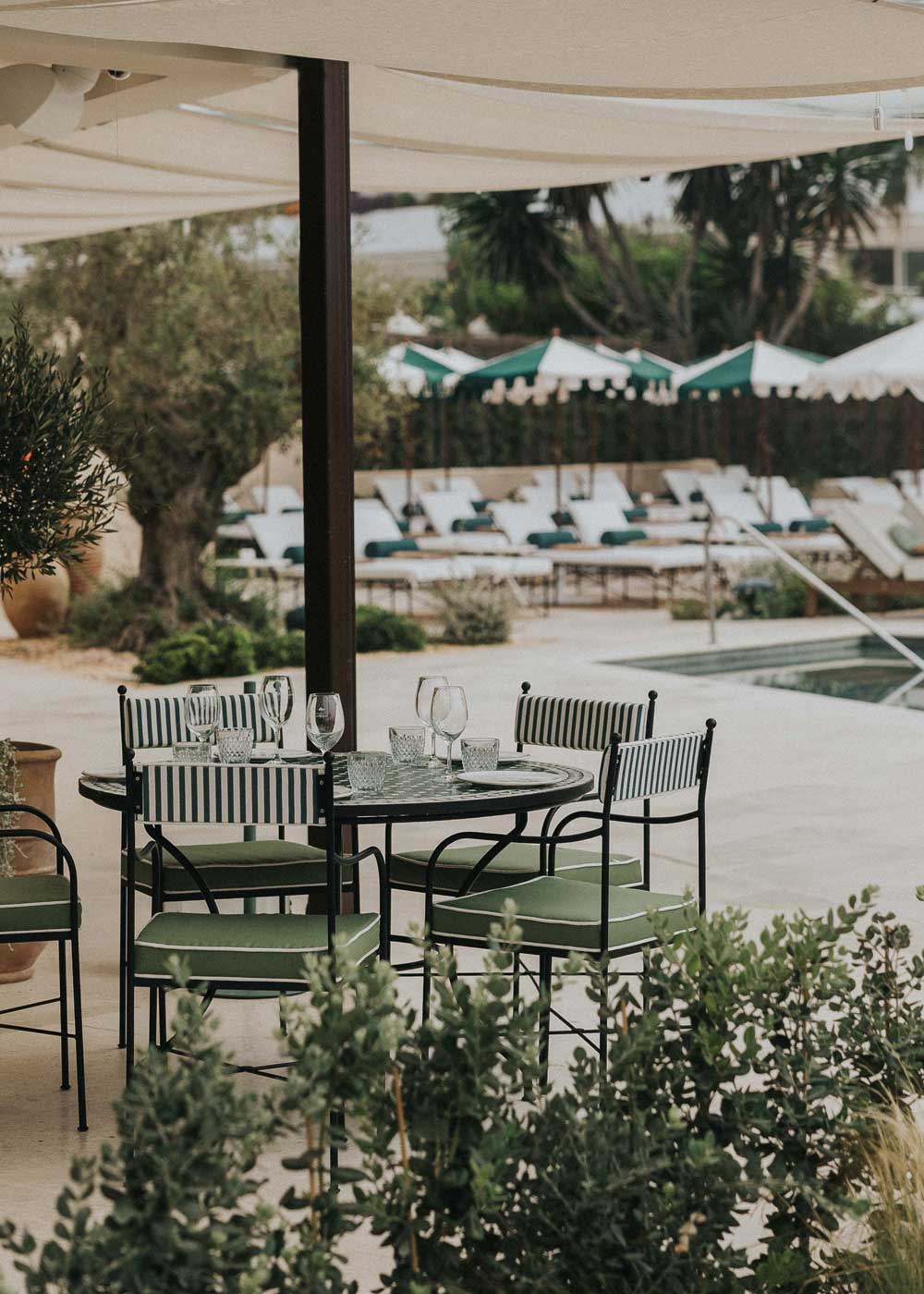 Mesa de exterior circular con estructura de hierro forjado acabado en negro y sobre en mosaico de azulejos.