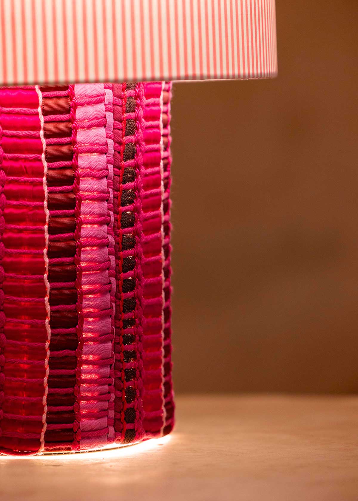 La lámpara N05 es una explosión de color. Perfecta para dar un toque de diversión y diseño a cualquier espacio. Con una base cubierta de tejido hecho en telar, combinando sedas, linos y diferentes texturas y una maxi pantalla de tejido de oxford de rayas rosas.