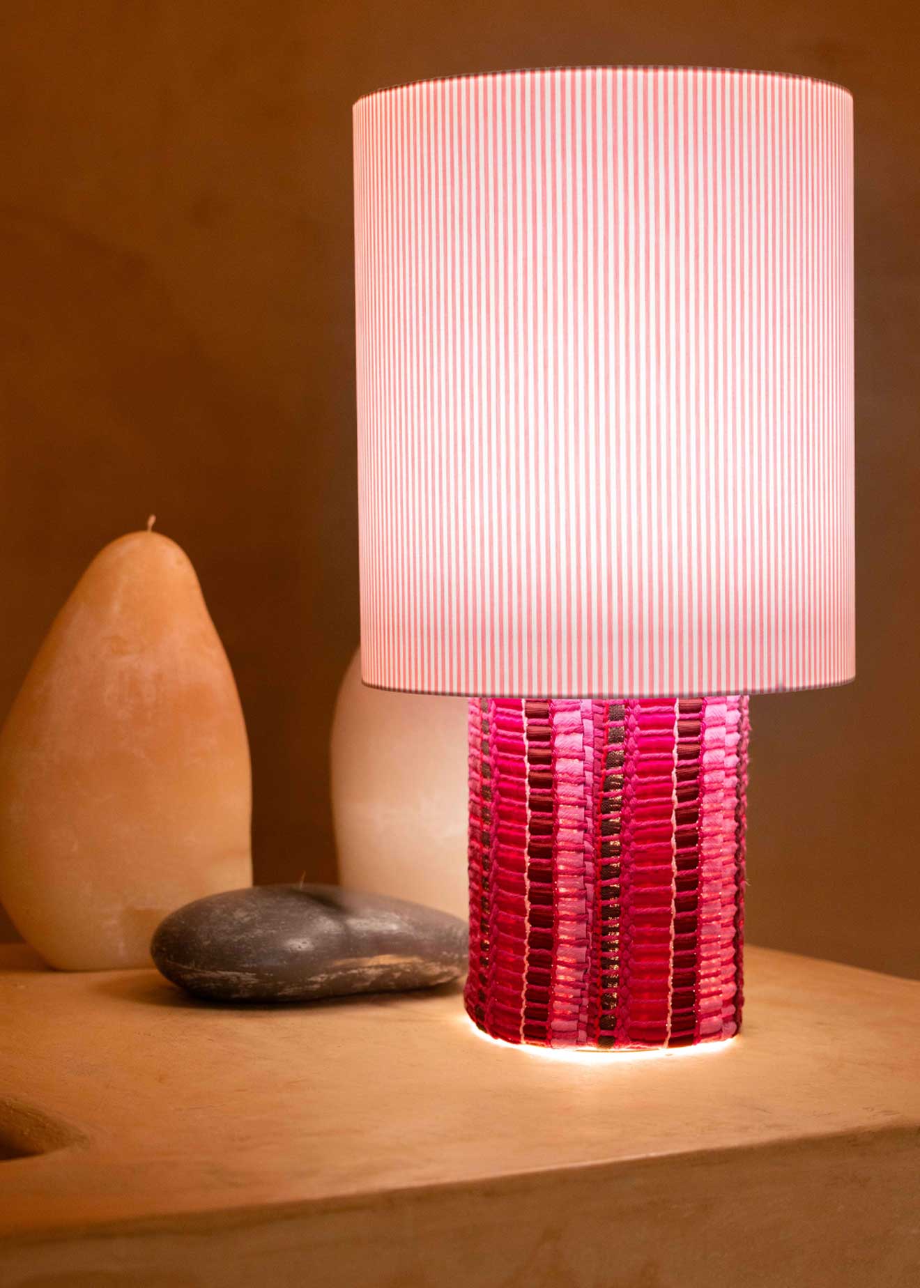 La lámpara N05 es una explosión de color. Perfecta para dar un toque de diversión y diseño a cualquier espacio. Con una base cubierta de tejido hecho en telar, combinando sedas, linos y diferentes texturas y una maxi pantalla de tejido de oxford de rayas rosas.