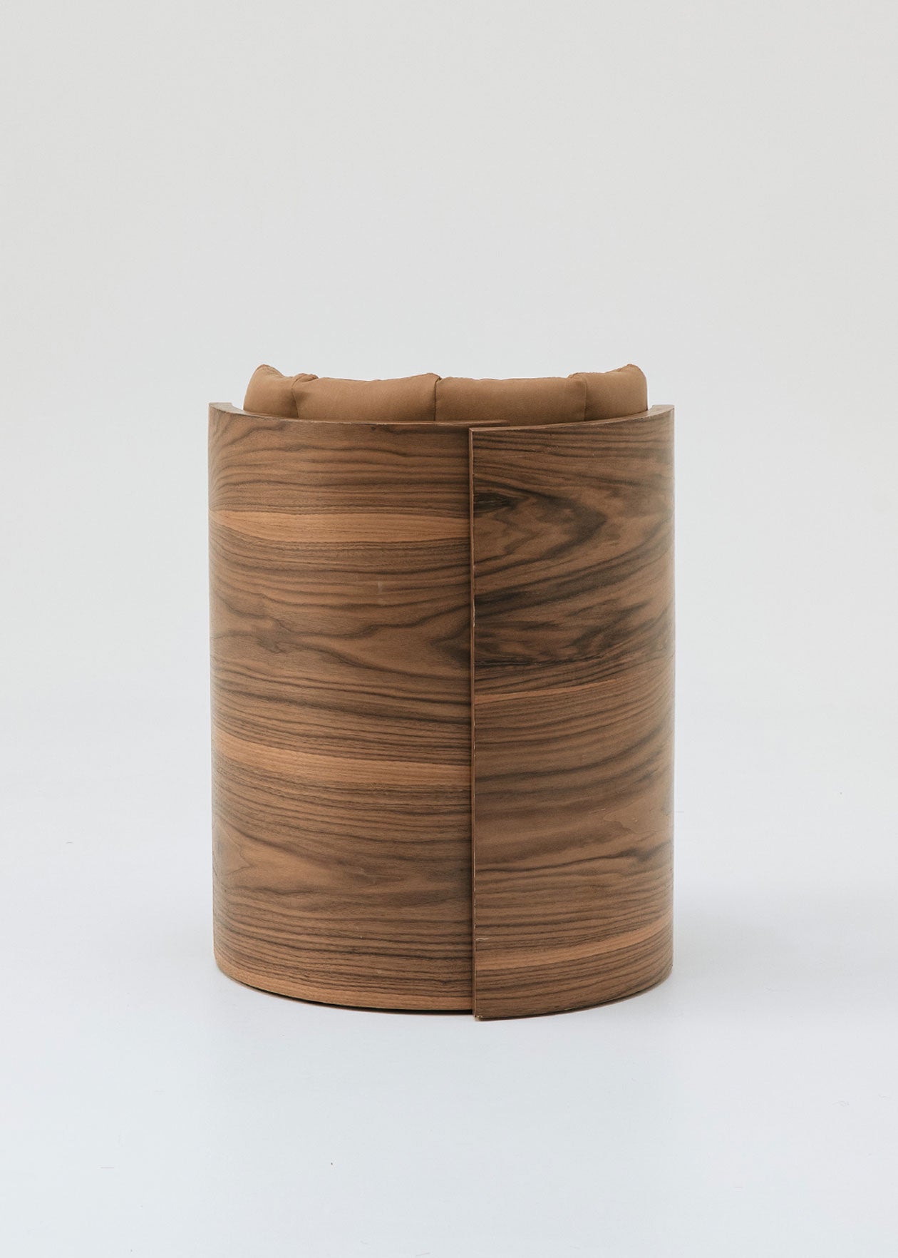 Butaca redonda con estructura de madera tapizada en dos telas, una de color beige para el asiento y una tela una polipiel camel para el respaldo.