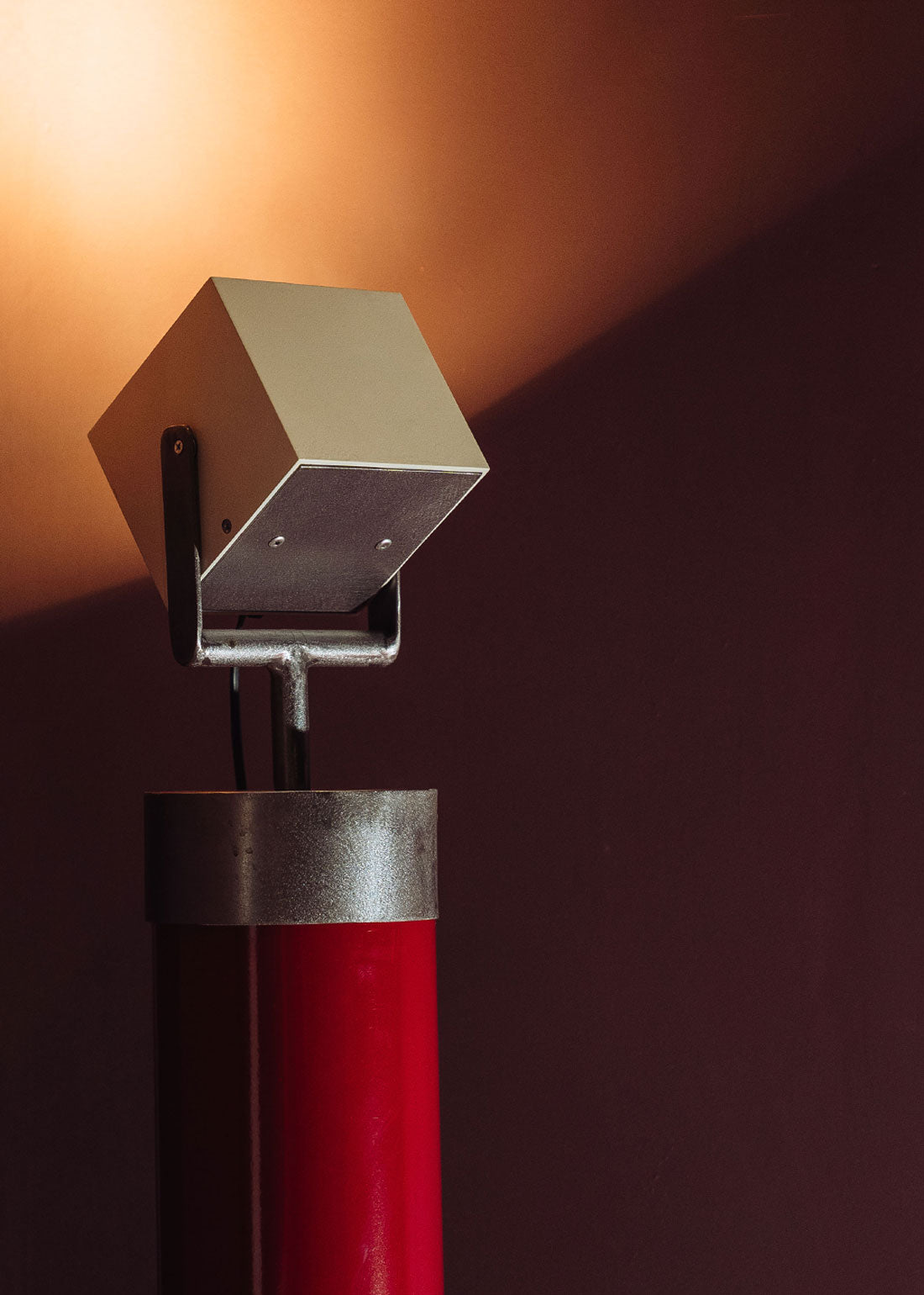 Foco orientable de pie de estilo industrial con soporte de acero lacado en rojo. Está diseñado para ir anclado al suelo.