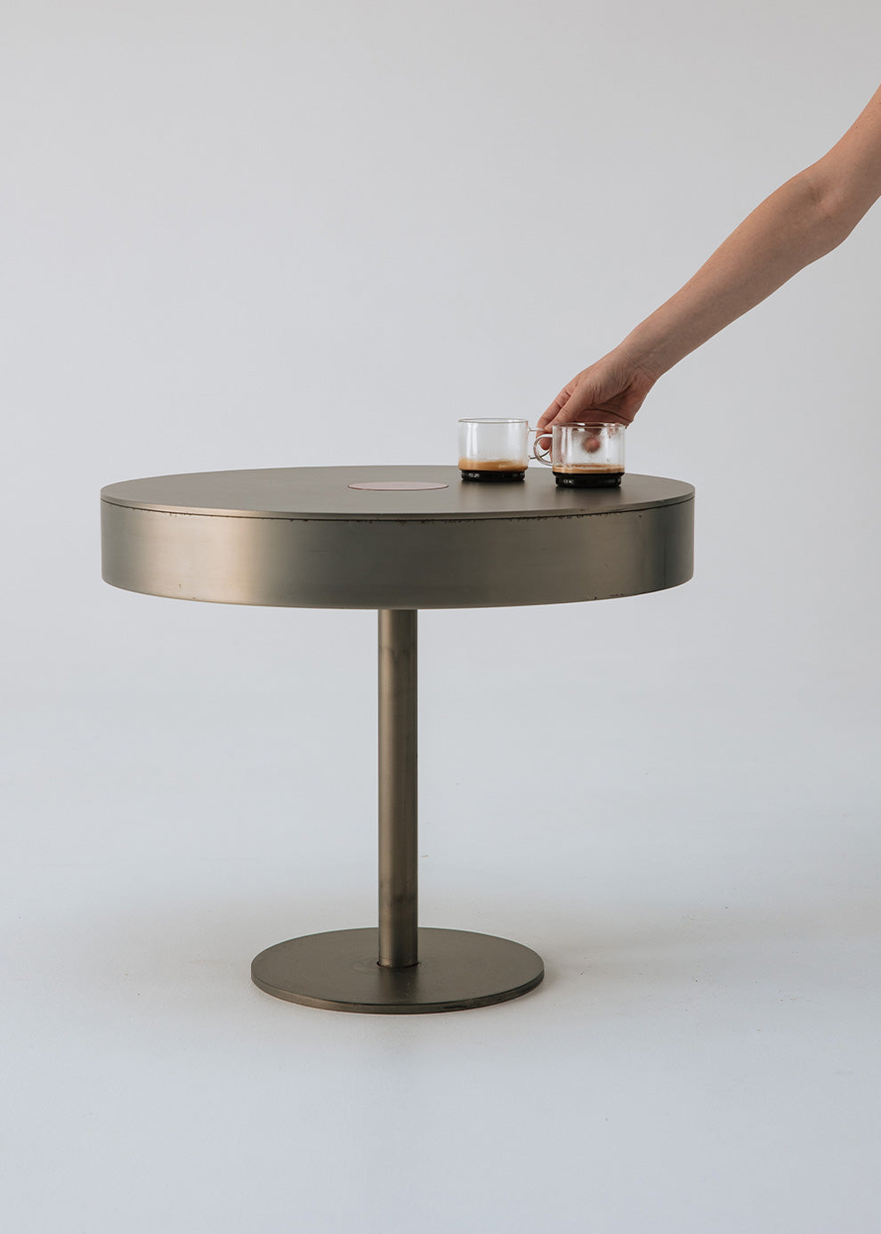 Mesa circular de centro realizada en acero con acabado mate y detalle lacado en rojo en el centro.