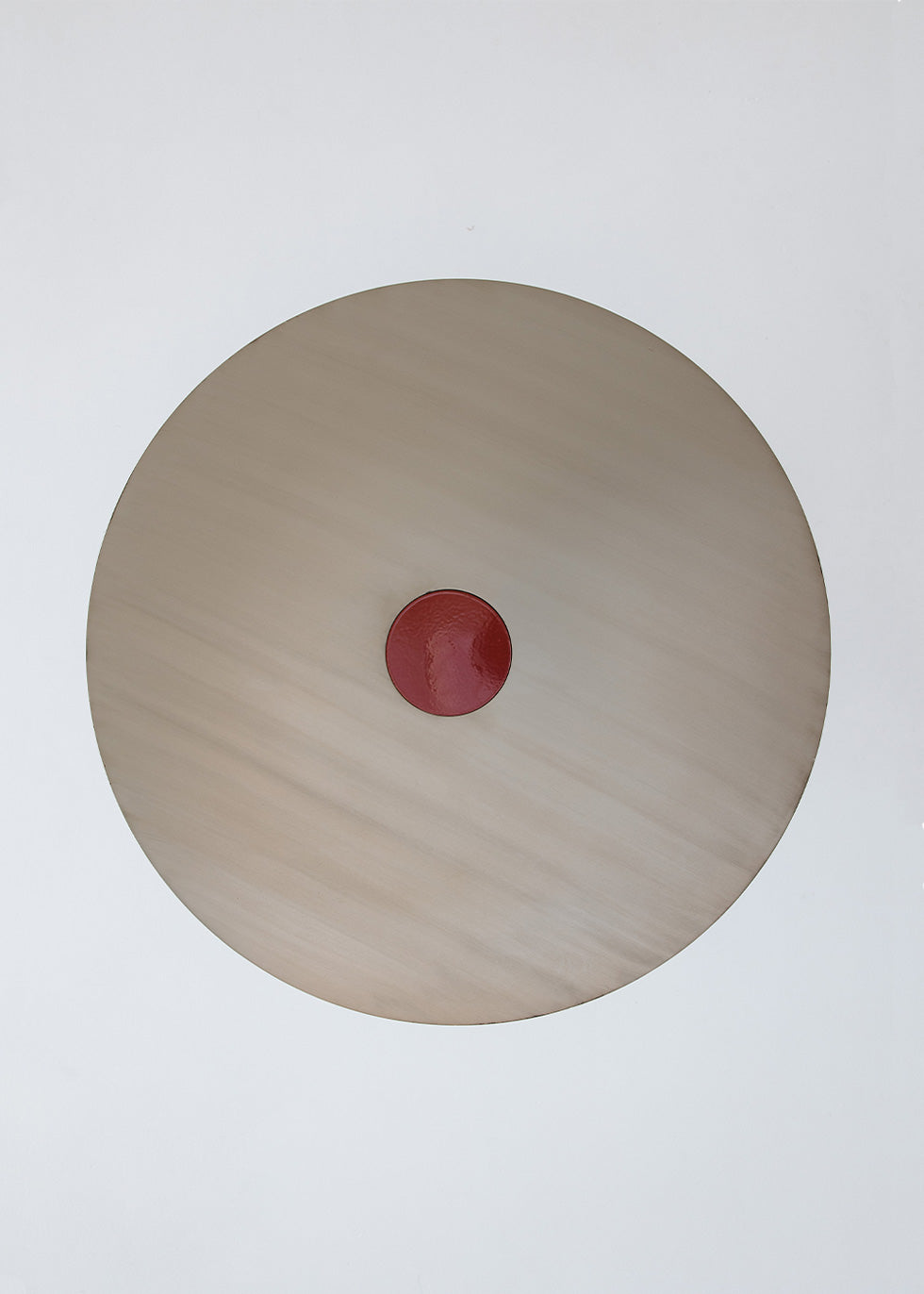 Mesa circular de centro realizada en acero con acabado mate y detalle lacado en rojo en el centro.