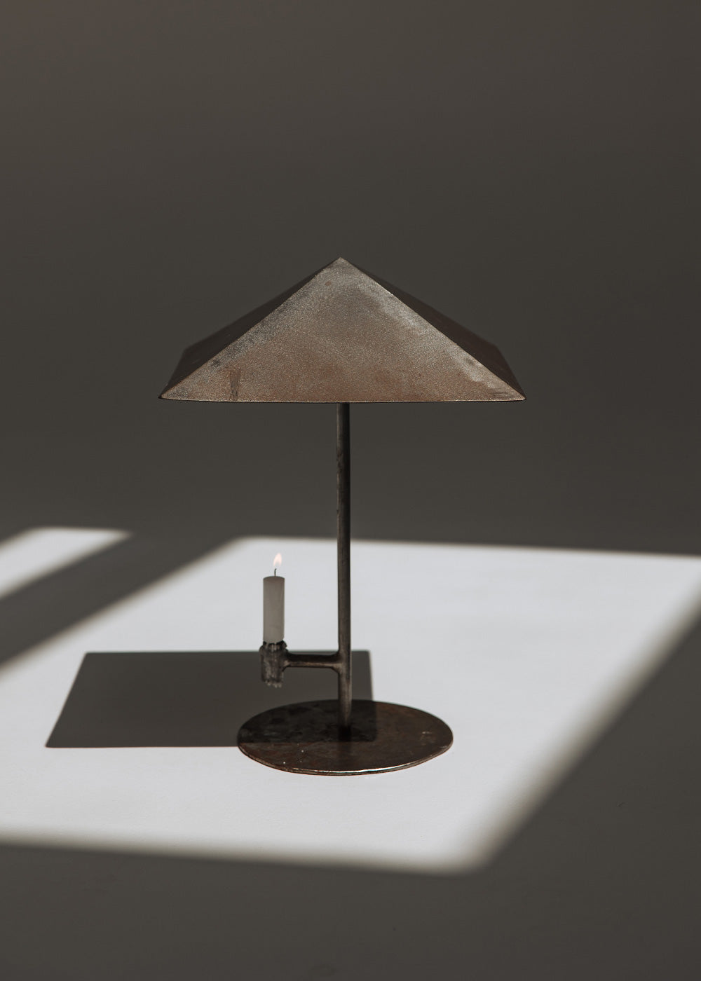 Portavelas metálico con forma de lámpara.