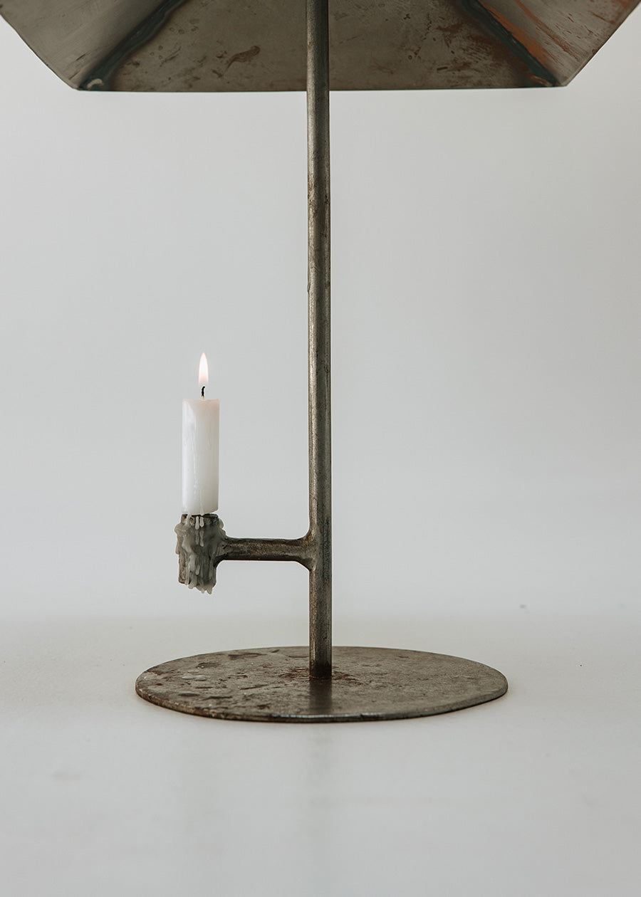 Portavelas metálico con forma de lámpara.