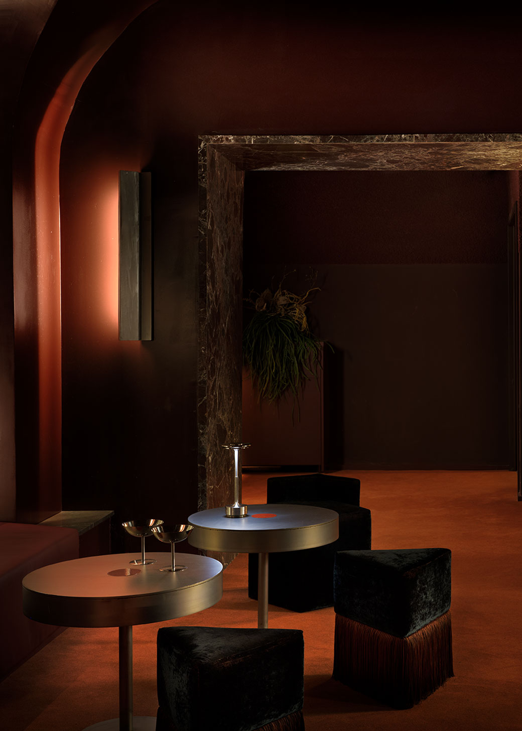 Puf triangular tapizado en terciopelo azul con detalle de flecos en la parte inferior.