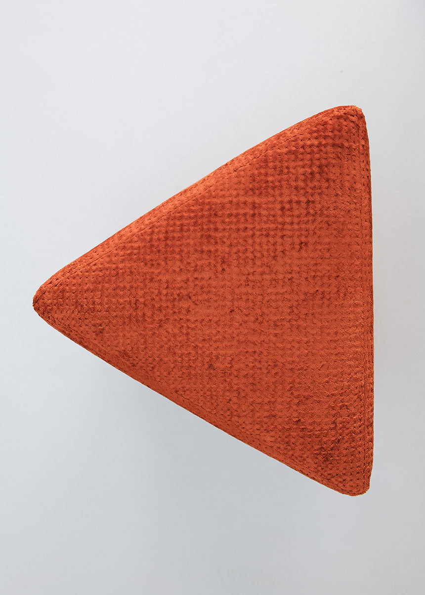 Puf triangular tapizado en tejido en tonos rojos, morados y burdeos.