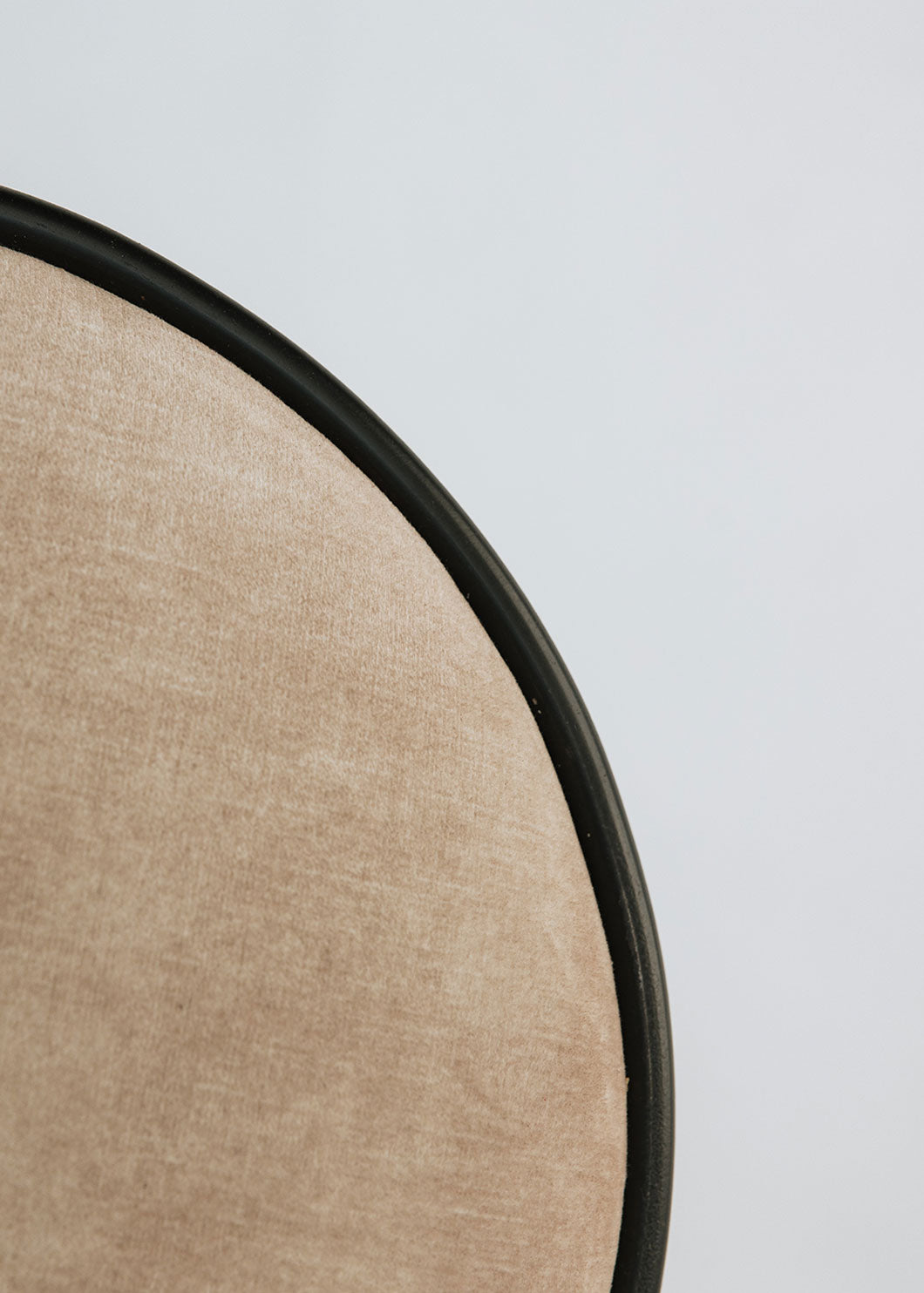 Taburete tapizado con estructura de hierro con detalle de piedra travertino. Un taburete alto con reposapiés y asiento tapizado en tela de terciopelo beige.