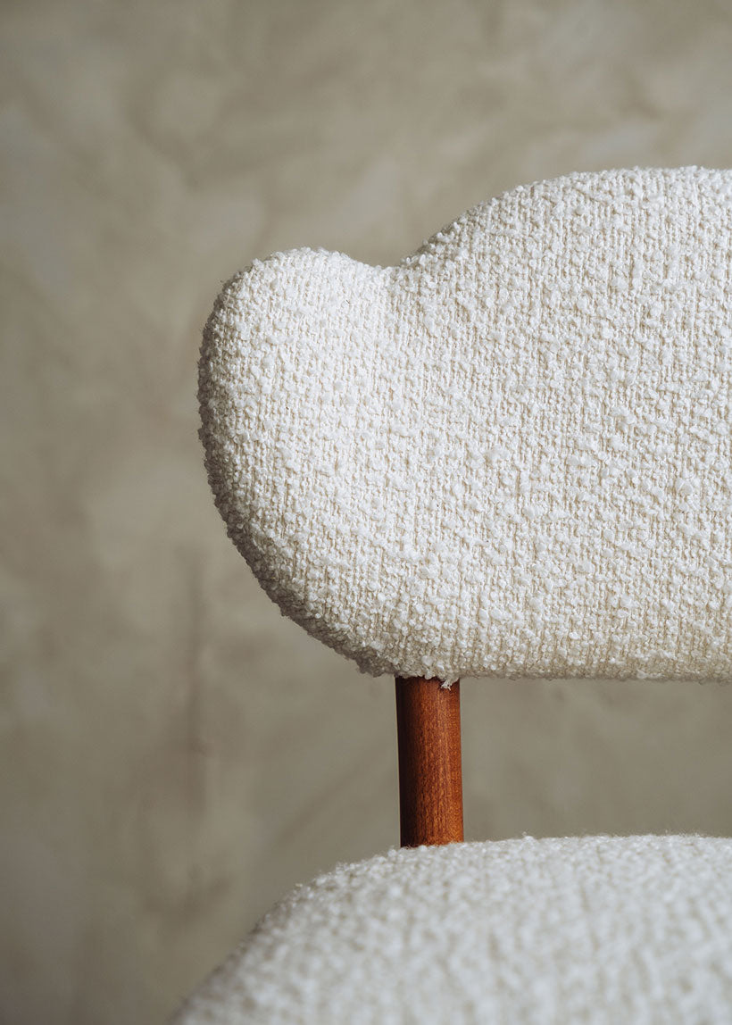 Silla de madera de haya tapizada en bouclé blanco.