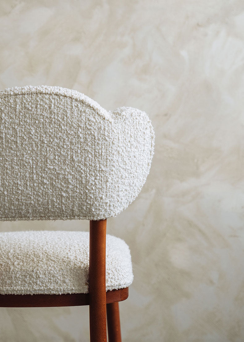 Silla de madera de haya tapizada en bouclé blanco.