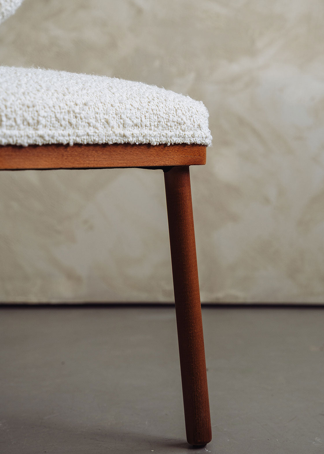 Silla de madera de haya tapizada en bouclé blanco.