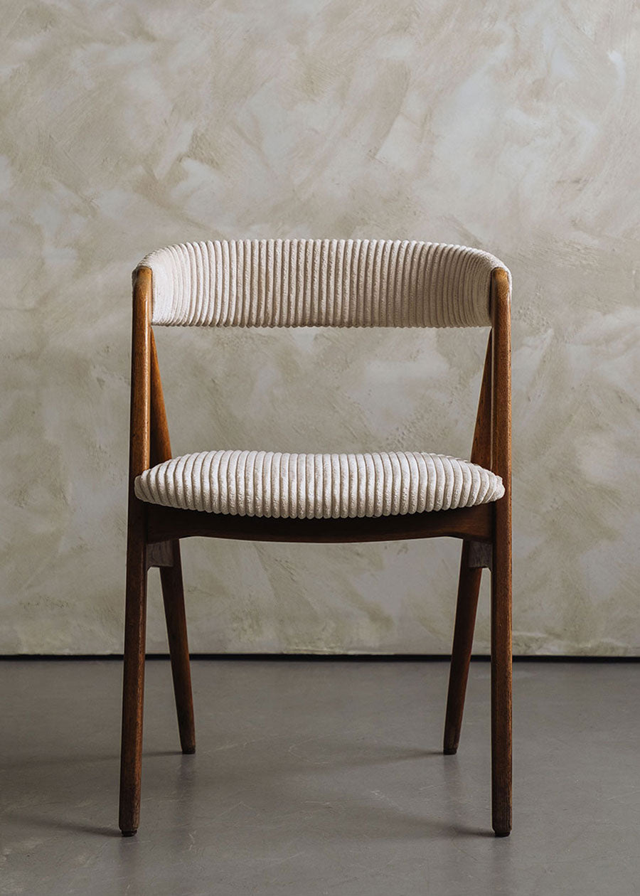 Silla de madera de haya tapizada en pana beige.