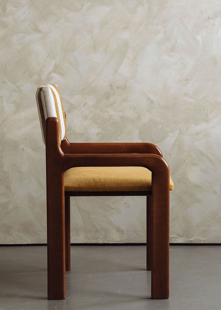 Silla de madera de haya con asiento tapizado en tela mostaza y respaldo con estampado de rayas.