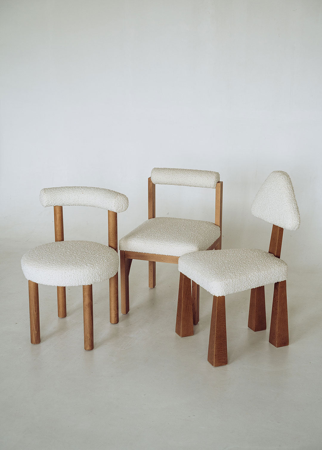 Silla de madera de haya tapizada en bouclé blanco con respaldo cilíndrico.