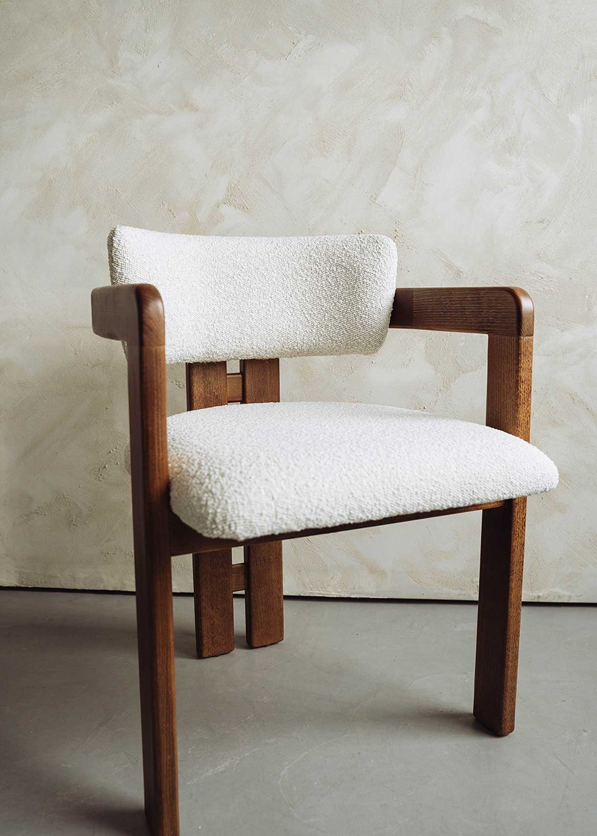 Silla de madera de haya con reposabrazos tapizada en terciopelo beige.