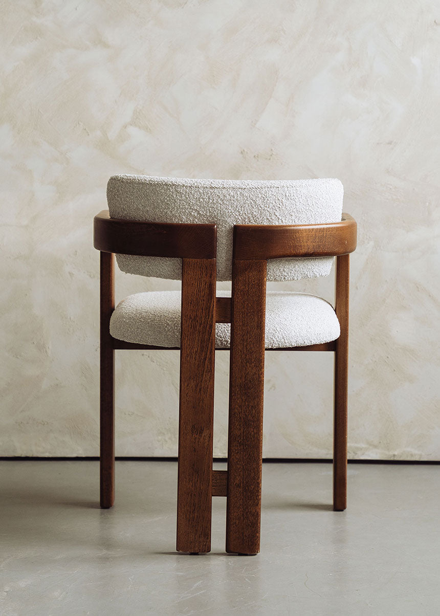 Silla de madera de haya con reposabrazos tapizada en terciopelo beige.
