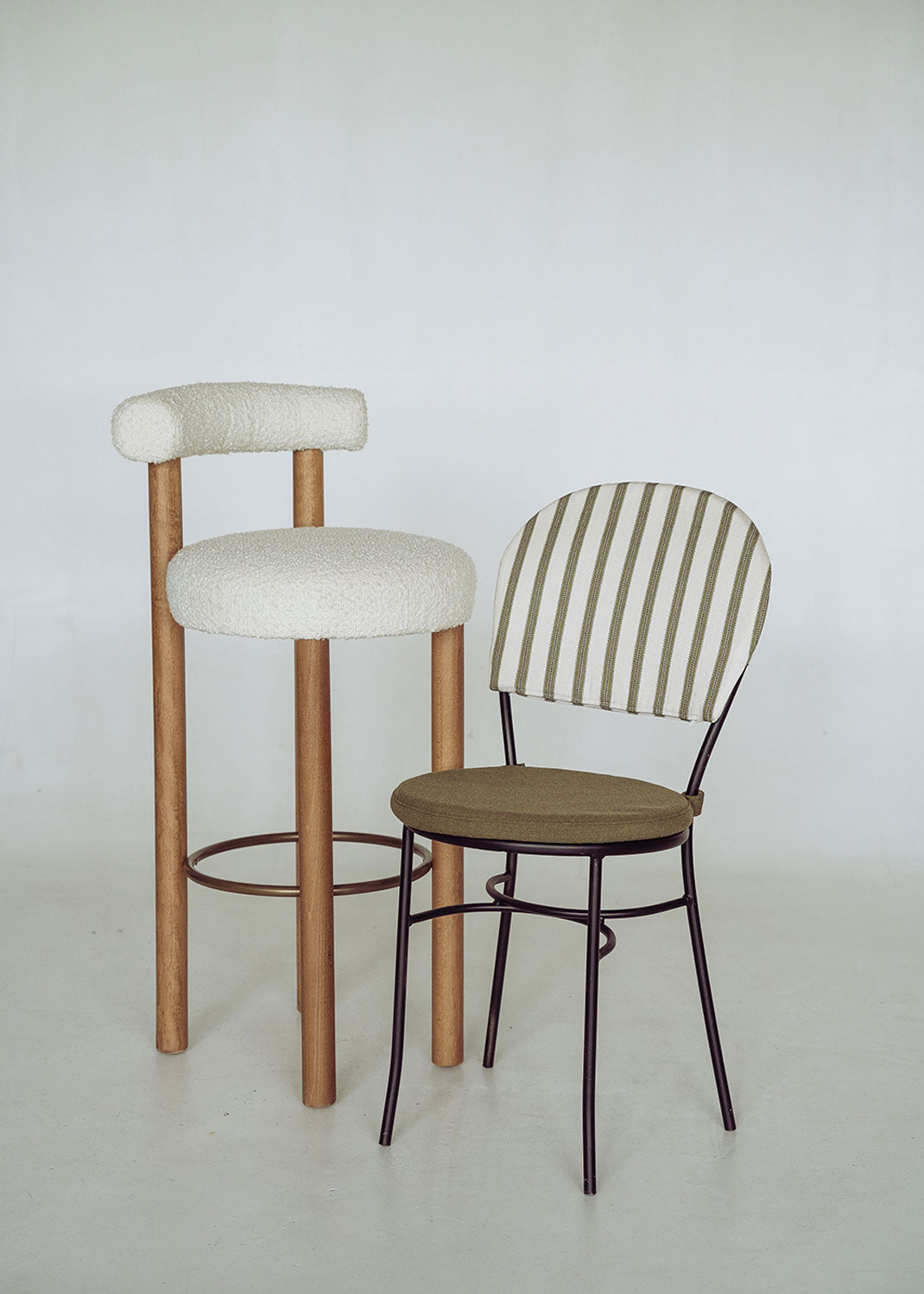 Taburete tapizado en tela beige con estructura de madera de haya. Un taburete alto con respaldo semicircular y reposapiés con acabado de latón incorporado.