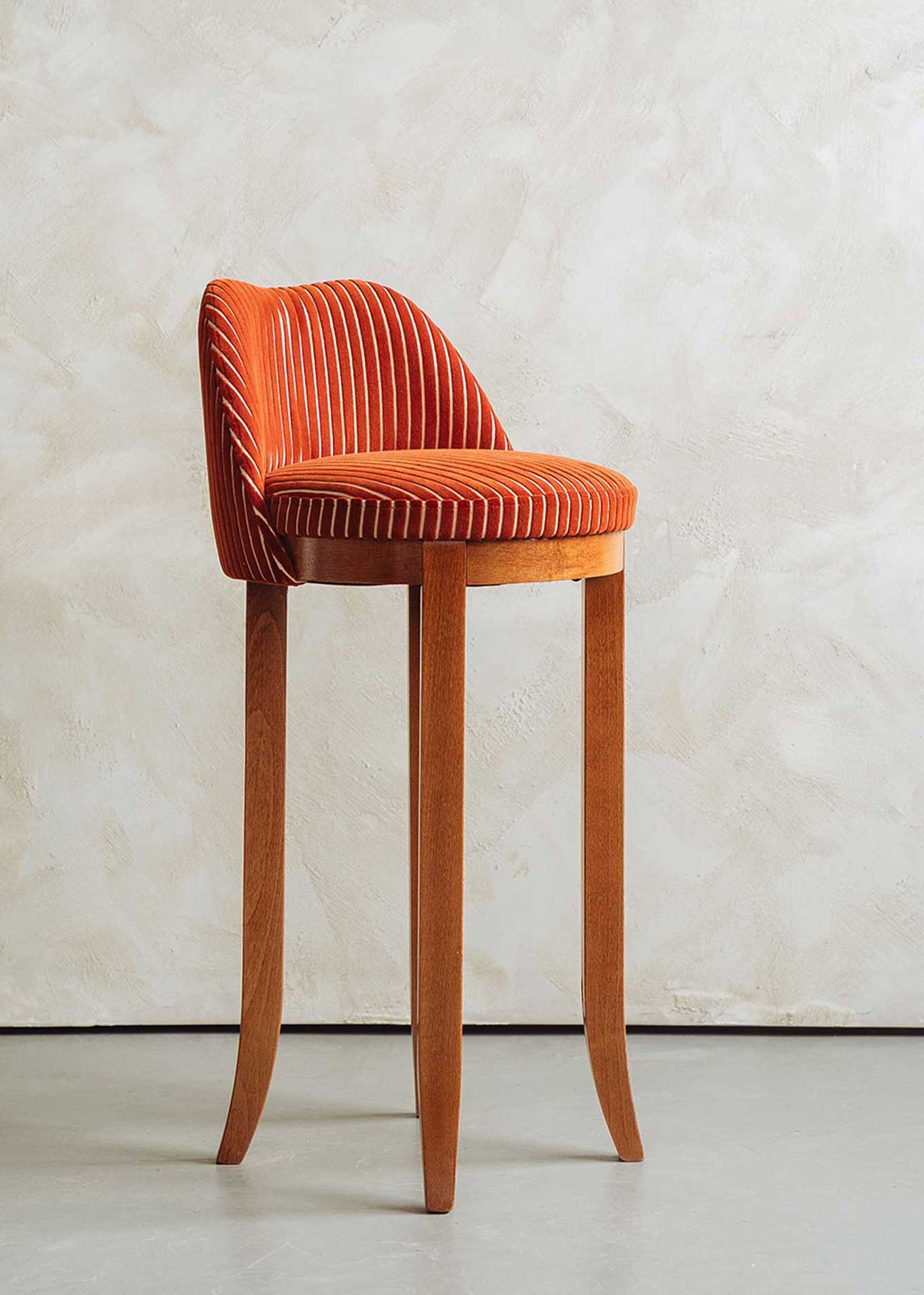 Taburete con respaldo tapizado en terciopelo caldera rayado con estructura de madera de haya.
