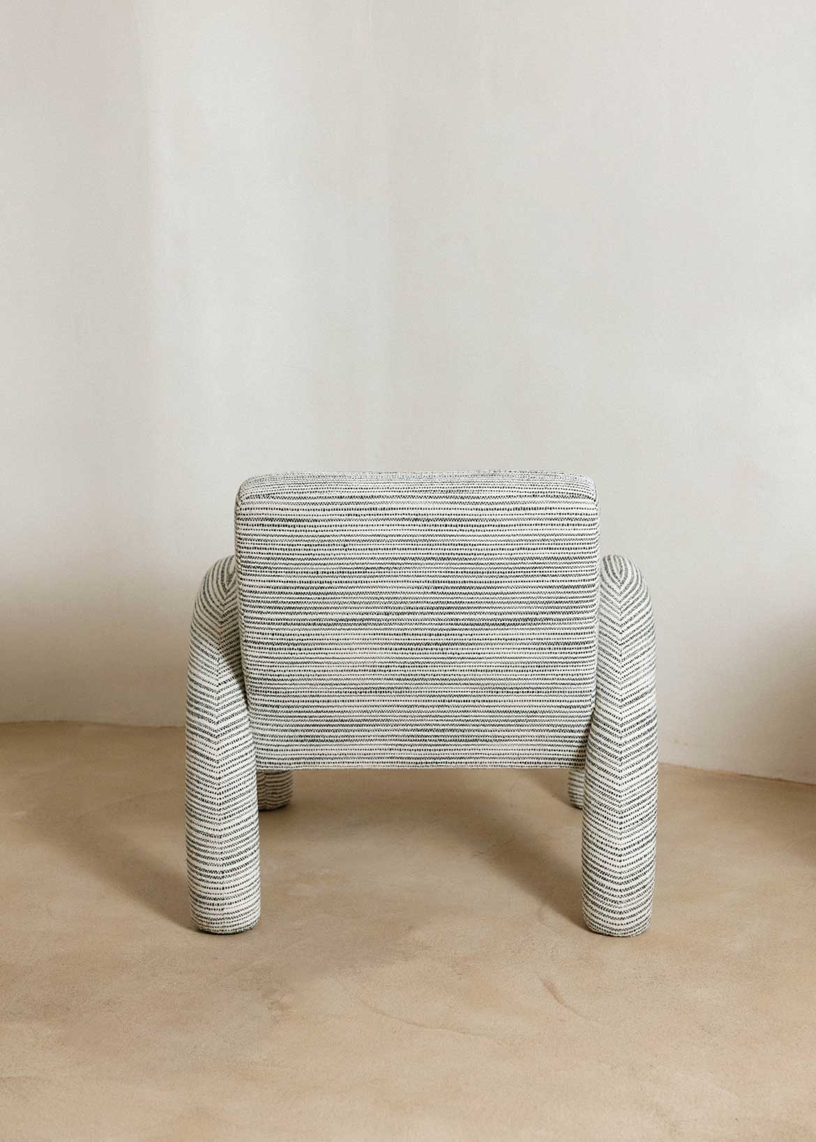 Butaca con reposabrazos tapizado con tela rayada azul y blanca.