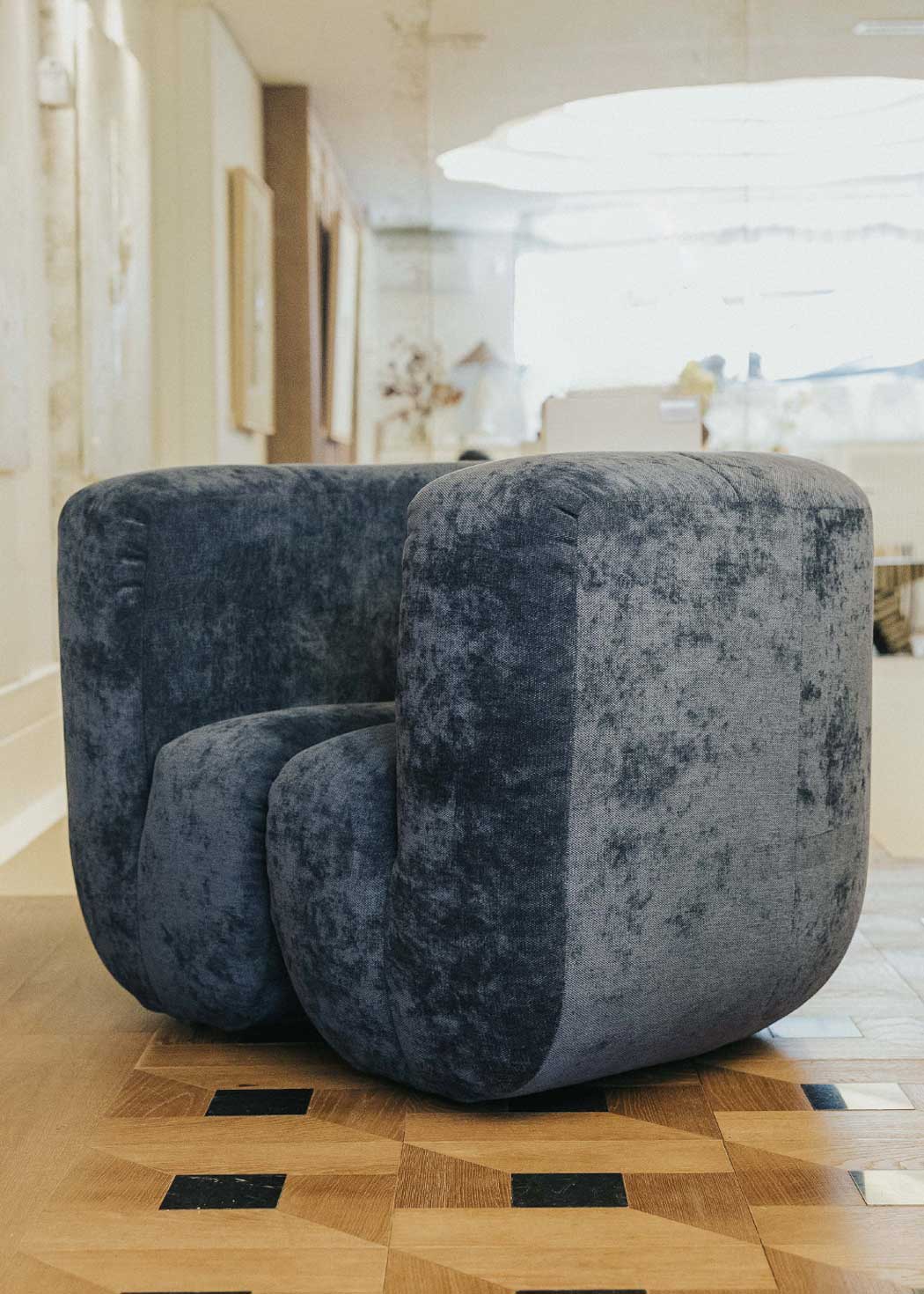 Sillón tapizado con tela de chenilla azul.