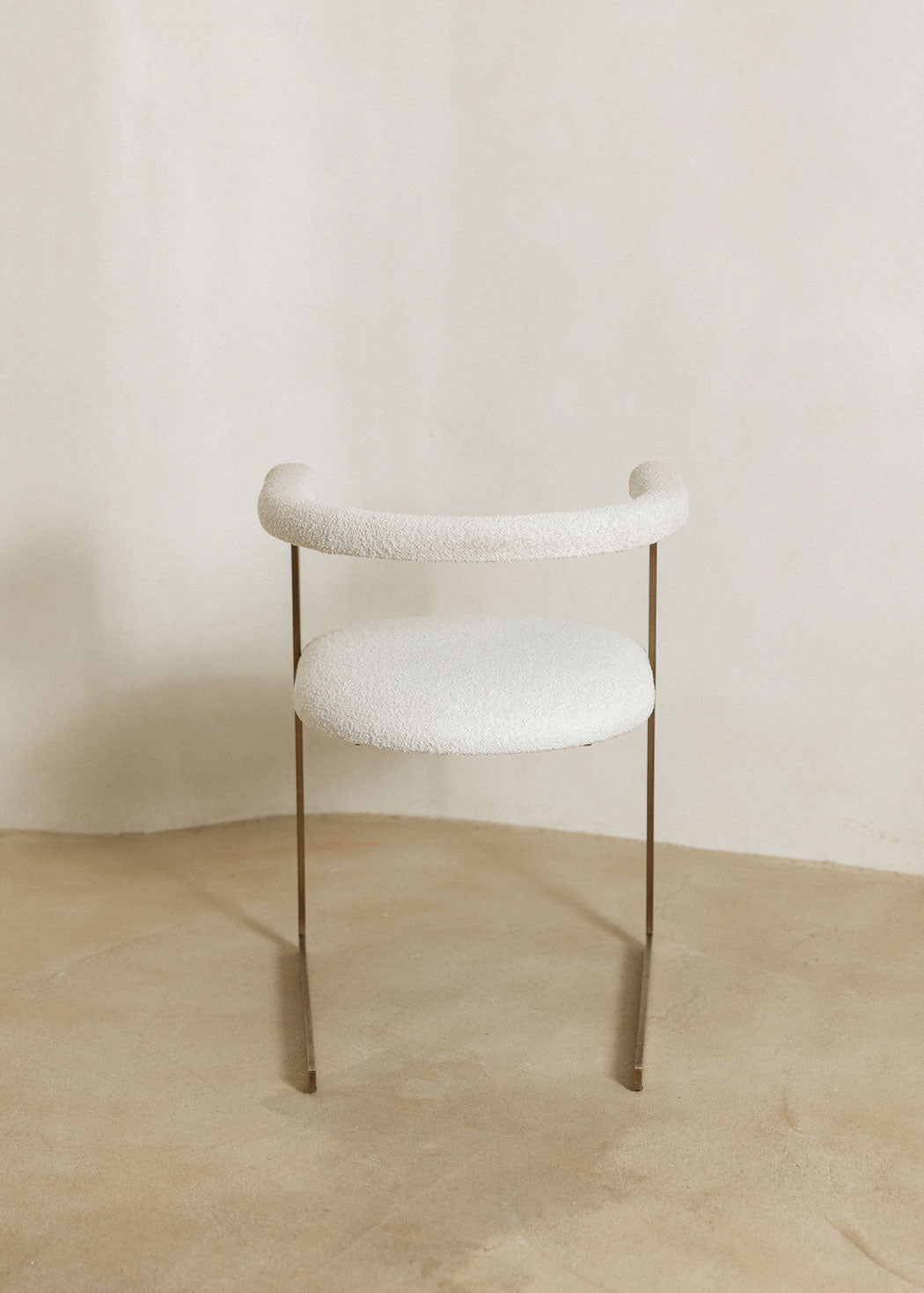 Silla de latón con acabado cepillado, tapizada con bouclé blanco.