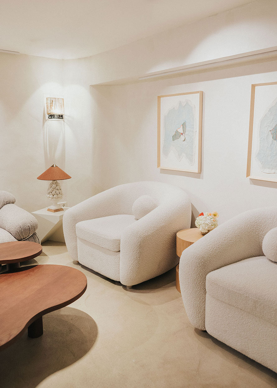 Sillón tapizado con tela bouclé blanca.