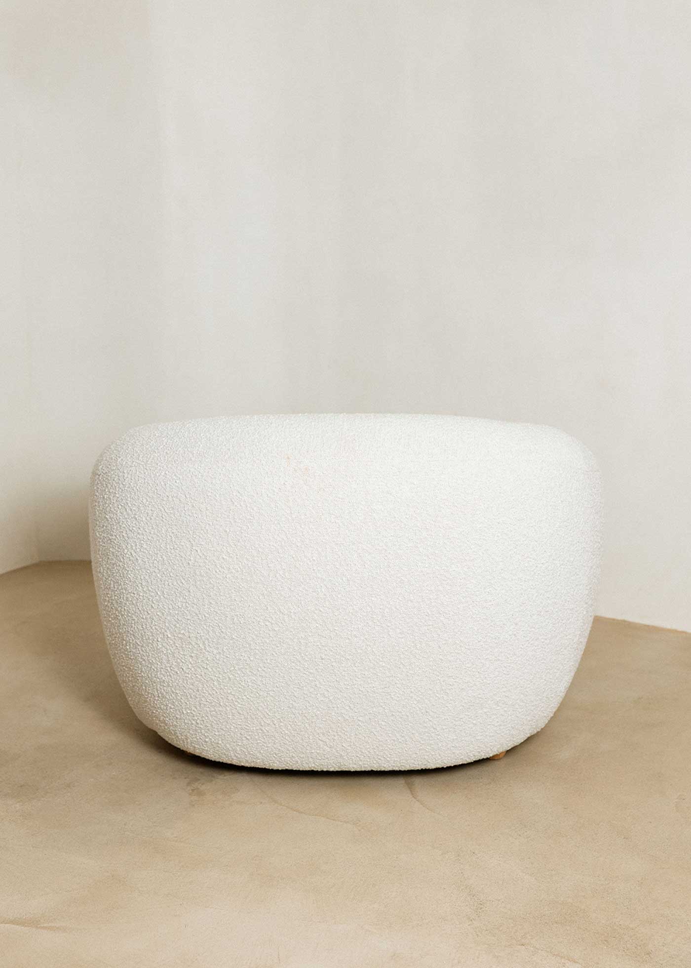 Sillón tapizado con tela bouclé blanca.