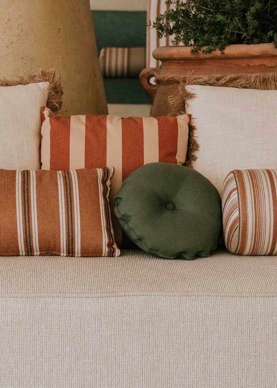 Almohadón circular con capitoné, tapizado en tela verde.