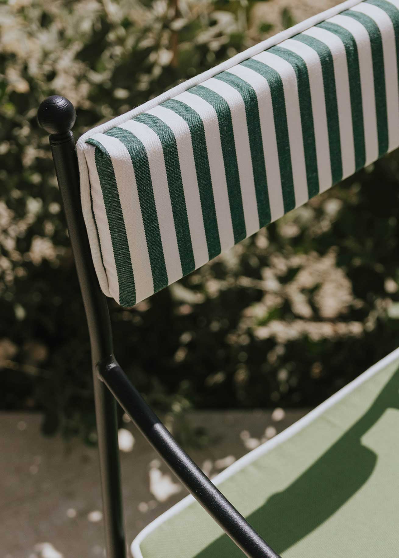 Silla de exterior con estructura de hierro negro tapizada en verde y blanco.