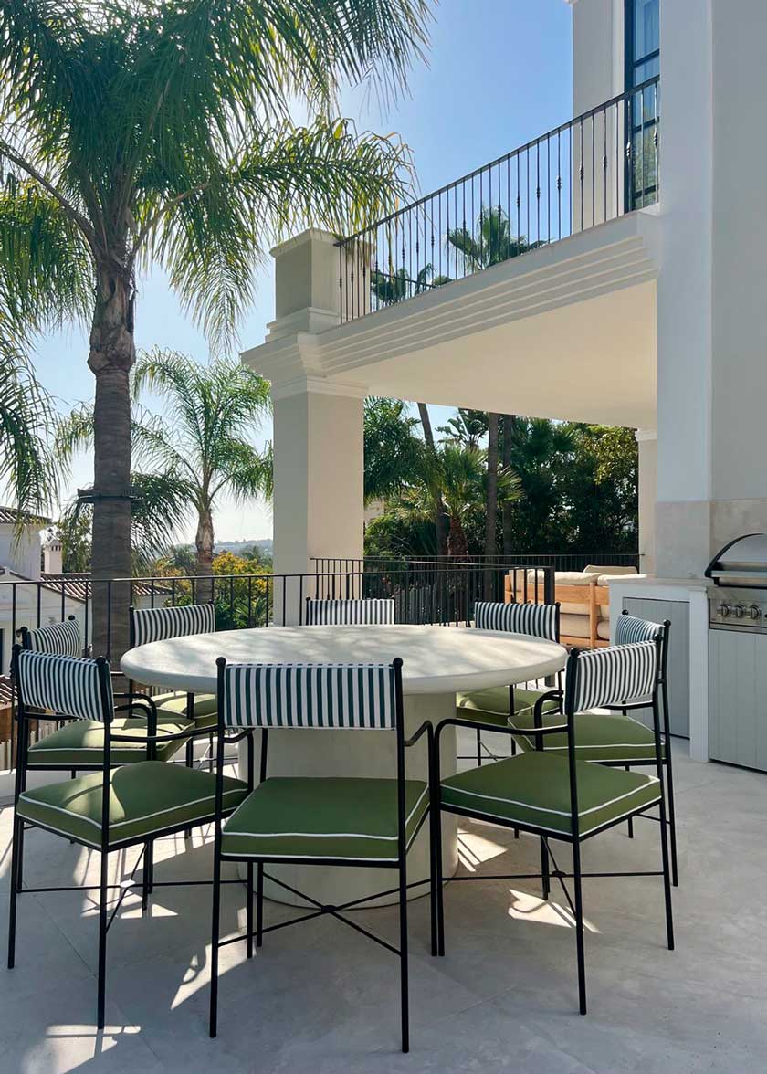 Silla de exterior con estructura de hierro negro tapizada en verde y blanco.