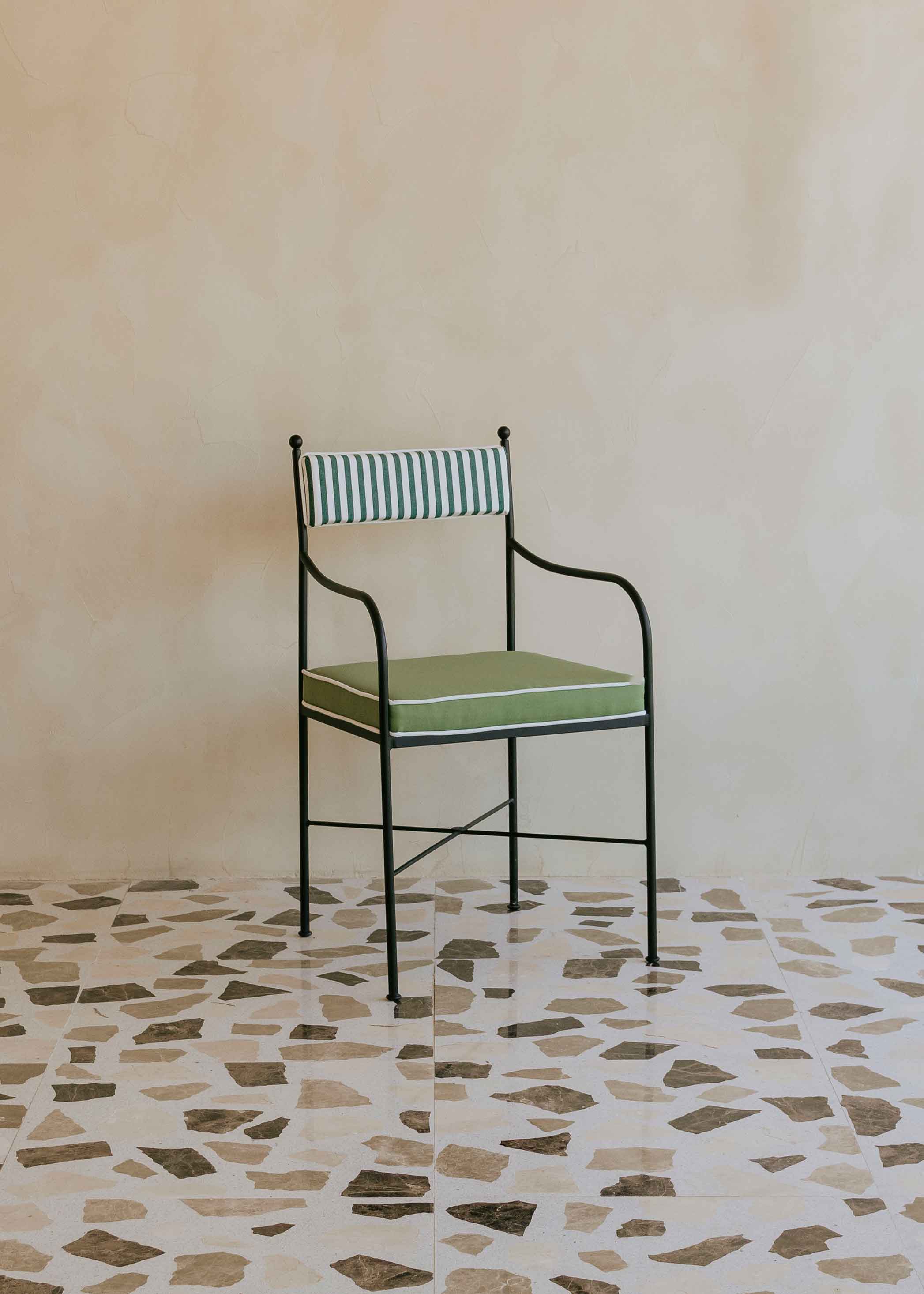 Silla de exterior con estructura de hierro negro tapizada en verde y blanco.