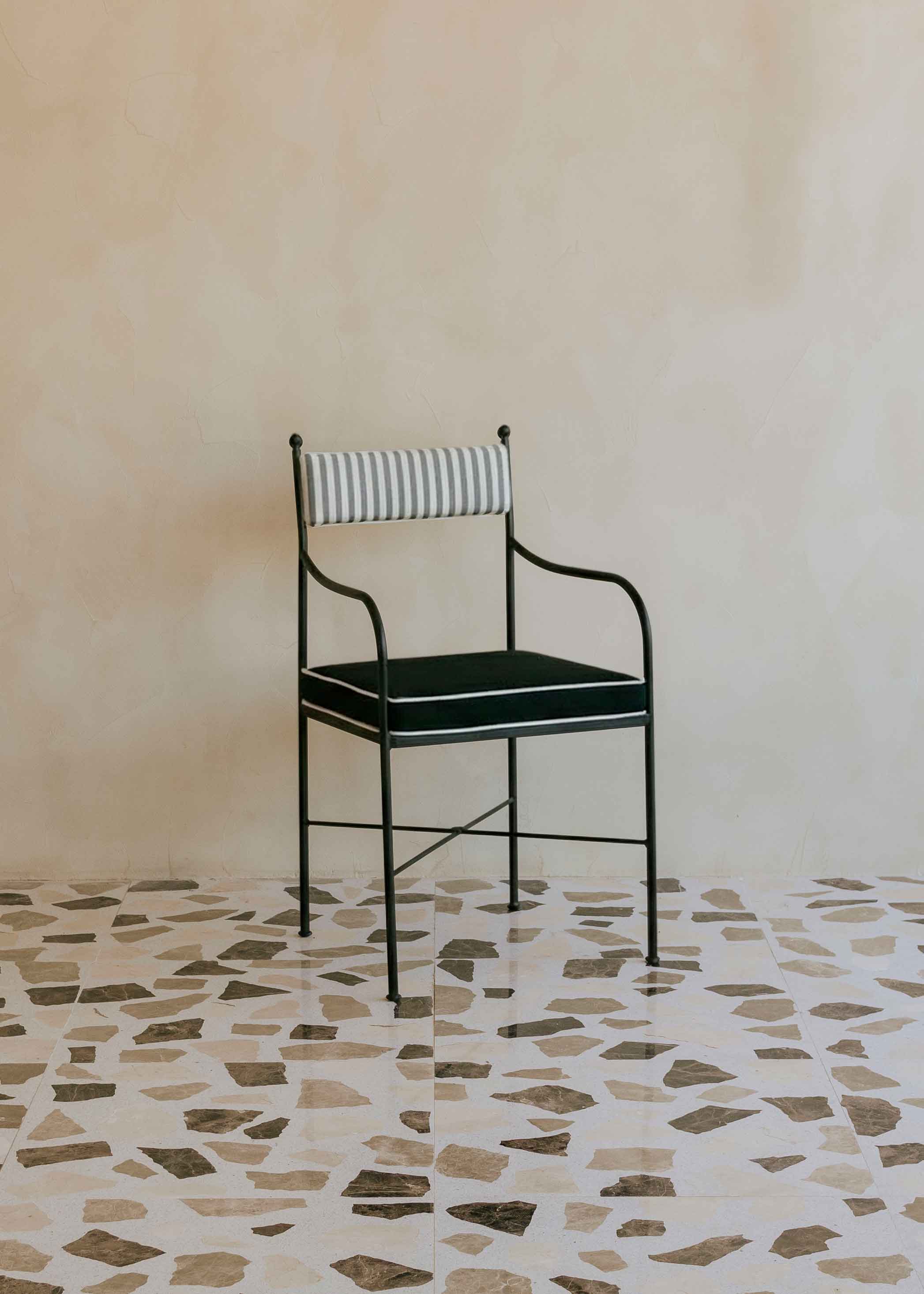 Silla de exterior con estructura de hierro negro tapizada en gris, negro y blanco.