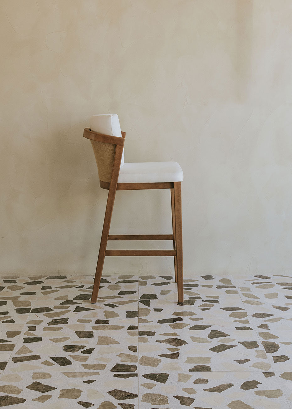 Taburete de exterior en madera de haya con respaldo tapizado en tela blanca.