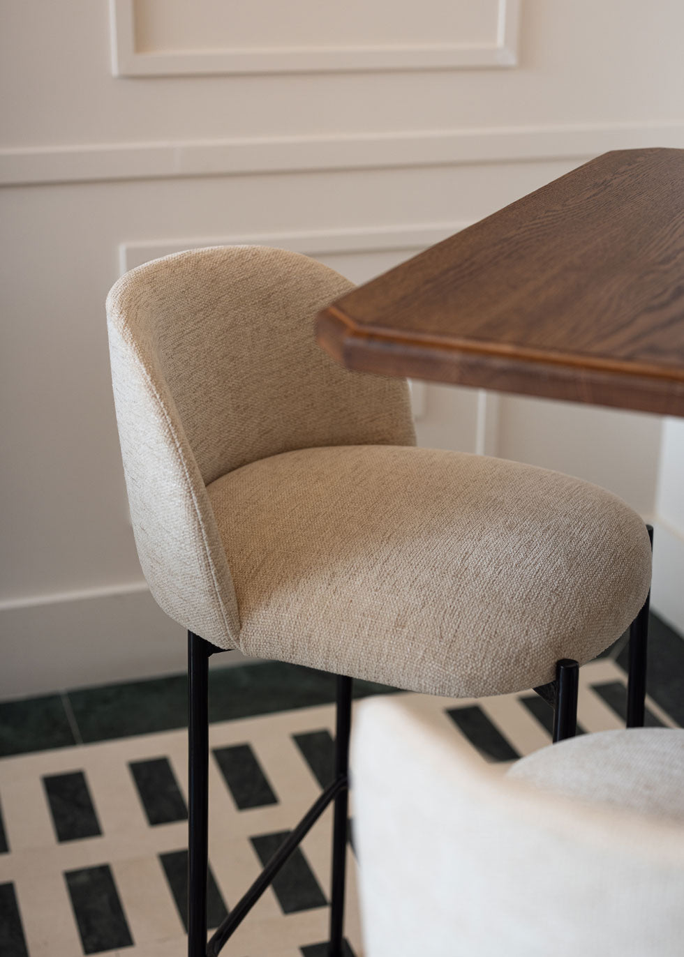 Taburete tapizado en tela beige con estructura de hierro acabado en negro